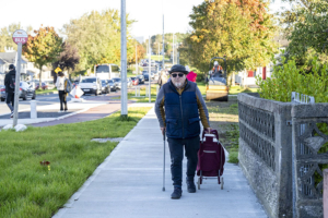 man walking with walking stick and wheeled shopping basket Galway