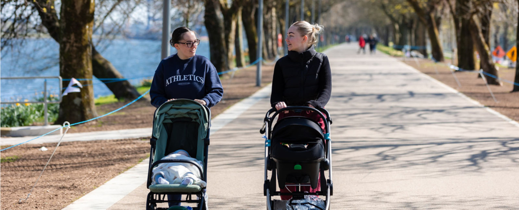 two women walking with buggies by the marina in Cork